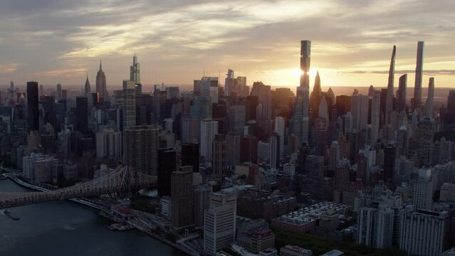 Aerial Shot of Midtown Manhattan Skyscrapers at Sunset. Beautiful view of Cityscape and Manhattan Bridge. Backlight. High Quality Footage Shot from Helicopter. New York City, United States.
