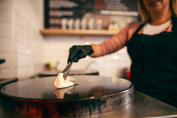 Close up of pancake house worker putting oil on hot plate and preparing it for baking crepes.