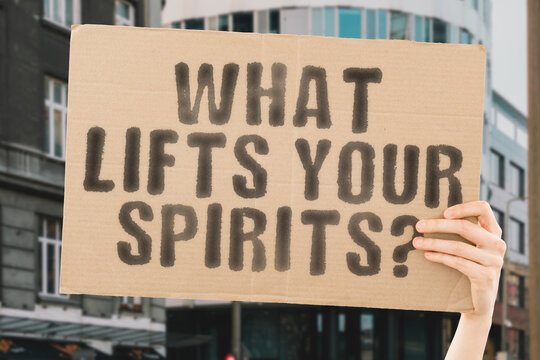 The question " What lifts your spirits? " is on a banner in men's hands with blurred background. Relax. Relaxation. Religion. Soul. God. Spiritual. Person. Lifestyle. Vision. Wellness. Calm. Lifted