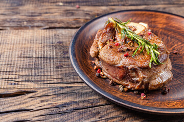 fried veal steak with seasonings in a frying pan, on a dark wooden background