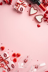 Valentine's Day concept. Top view vertical photo of gift boxes wine bottle heart shaped candles chocolate candies and two glasses with confetti on isolated light pink background with empty space