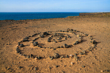 Fototapeta na wymiar Concentric circles made out of stones in the desert over Playa de la Escalera (Staircase Beach) on the western coast of Fuerteventura in the Canary Islands, Atlantic Ocean, Spain