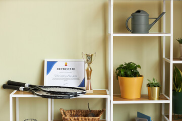 Background image of graphic white shelves in home interior with decor items and focus on education certificate, copy space