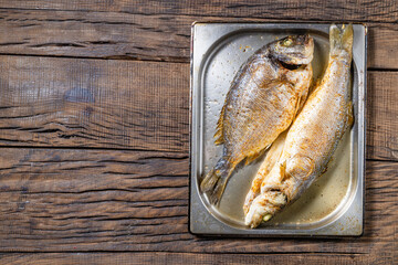 fried fish sea bass and dorado on a metal plate on a dark wooden background, rack of lamb