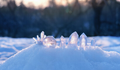 Clear quartz minerals on snow, natural blurred winter background. Gemstones for esoteric Crystal...