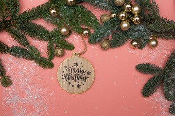 Green branches of a Christmas tree with artificial snow decorated with golden Christmas balls and a...