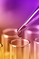 Test tubes with blue liquid water samples and pipette. Pipette dropping sample into test tube. Laboratory glassware, science laboratory research concept.