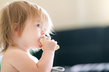 A cute toddler is having a snack. Portrait of a child eating a banana