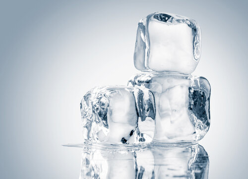 Natural crystal clear melting ice cubes on white background with reflection.