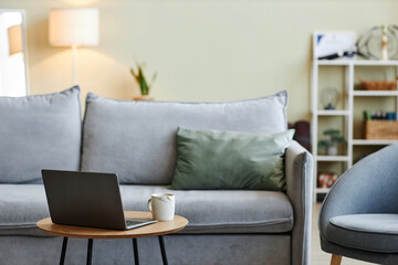 Close up of laptop on coffee table in stylish living room interior with comfortable furniture, copy space