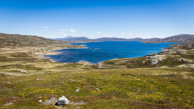 Beautiful landscape view in Norway with mountains, meadows, a mountain hut village and the Vinstre lake with blue water