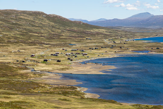 Beautiful scandinavian landscape view in Norway with mountains, meadows, a mountain hut village and the Vinstre lake with blue water