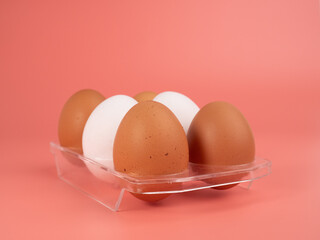 Chicken eggs on a pink background. White and brown egg on a pink background.
