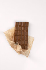 Top view of dark chocolate bar in craft package on gray wooden background