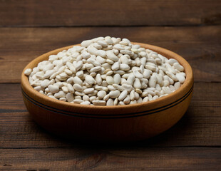 White raw beans in wooden plate on a wooden background