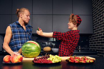 Happy couple standing in kitchen at home preparing together yummy dinner on first dating, spouses chatting enjoy warm conversation and cooking process, caring for health, eating fresh vegetable salad