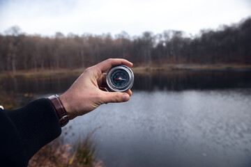 Fototapeta premium Man holding a compass in front of a lake