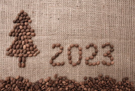 Merry Christmas and New Year greeting card. numbers 2023 and Christmas tree are made from coffee beans on fabric with burlap texture. View from above. New Year concept background - Powered by Adobe