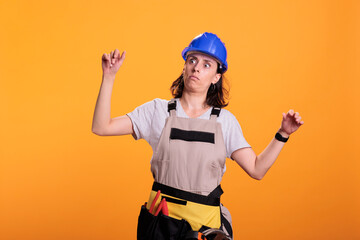 Woman engineering constructor acting dizzy and tired, standing over yellow background and losing balance. Young contractor builder experiencing dizziness and being thoughtful, studio shot. - obrazy, fototapety, plakaty