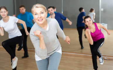 Cheerful middle aged woman enjoying active dances in modern dance studio