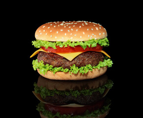 Big hamburger with big beef cutlet on black background with reflection