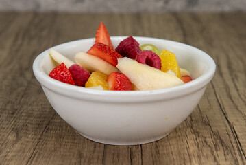 Generous bowl of fresh sliced fruit including strawberry, pear, and orange