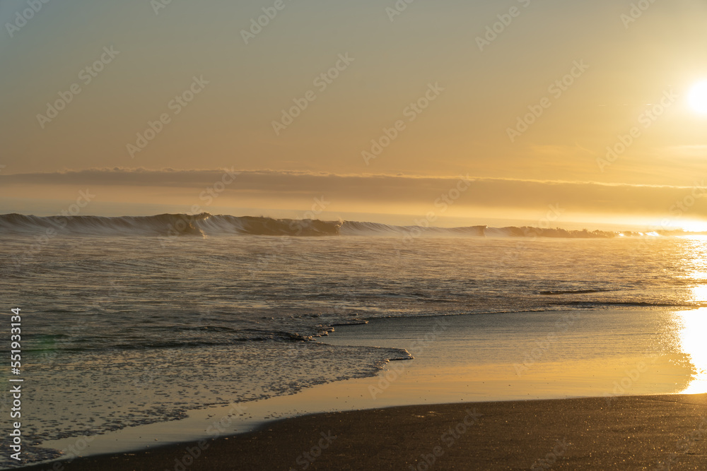 Wall mural golden coastal sunrise on surf beach papamoa, tauranga