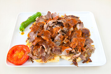 Turkish and Arabic Traditional Ramadan doner kebab with tasty tomato sauce and rice or turkish pilav in white plate on wood table background. ( Pilav ustu doner)