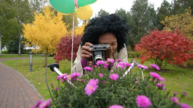 Astonished female tourist snapping scenic views with colorful greenery around. Beautiful, stylish lady taking pictures of charming purple flowers. High quality 4k footage