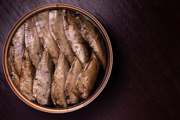close-up photo of canned fish - sprats in oil - on a dark wooden background