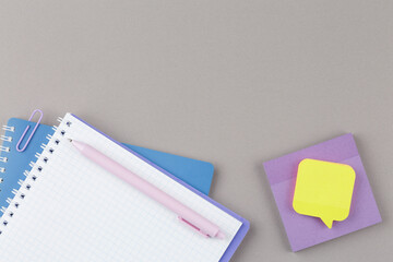 Notepad with school supplies on gray desk.