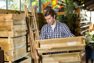 Attentive man choosing wooden pallets in garden shop
