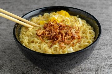instant noodle with fried shallots on black bowl with chopstick