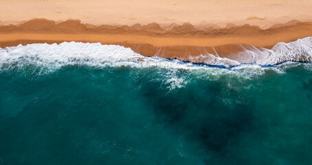 Obraz na płótnie Canvas Drone view of the foamy sea waves and sandy beach
