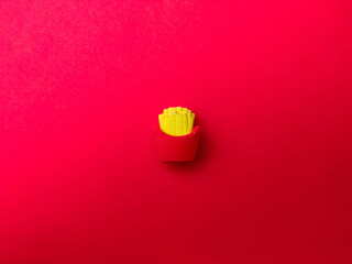 Top view of toy fried potatoes on a red background.