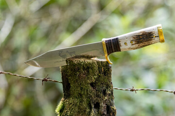 Close up of a mountain knife stuck on a rural fence post - obrazy, fototapety, plakaty