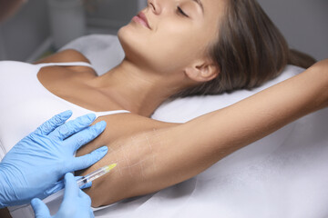 Obraz na płótnie Canvas Young woman getting armpits injection in salon