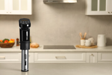 Thermal immersion circulator on white table in kitchen, space for text. Sous vide cooking