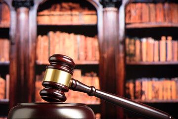 Close up of wooden judge gavel. Blury book library background