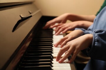 Obraz premium Young woman with child playing piano, closeup. Music lesson