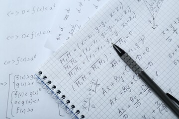 Notebook with different mathematical formulas and pen, top view