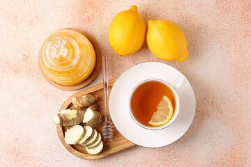 Flat lay composition of tea, honey, lemon and ginger on beige textured table