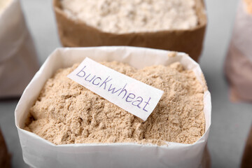 Sack with buckwheat flour on blurred background, closeup