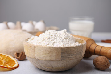 Fototapeta na wymiar Bowl of flour and other ingredients on white table