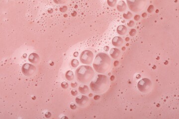 Tasty pink smoothie with bubbles as background, closeup