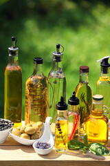 Different cooking oils and ingredients on wooden table against blurred green background