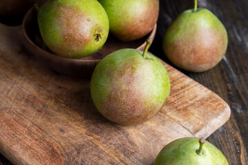 Whole ripe green pears on the board