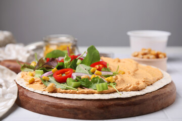 Tortilla with hummus and vegetables on table, closeup