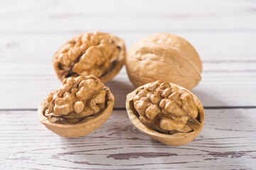 Walnut kernels and whole walnuts on wooden table.