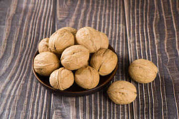 Walnut kernels and whole walnuts on wooden table.